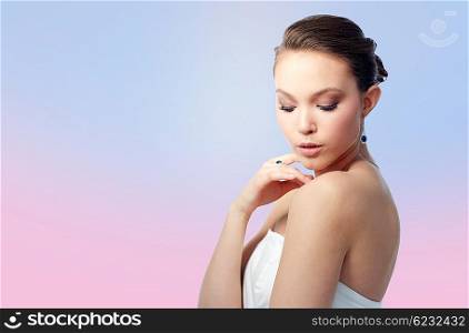 beauty, jewelry, people and luxury concept - beautiful asian woman or bride with earring and finger ring over rose quartz and serenity gradient background