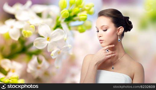 beauty, jewelry, people and luxury concept - beautiful asian woman or bride with earring, finger ring and pendant over natural spring lilac blossom background