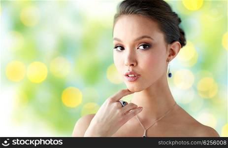 beauty, jewelry, people and luxury concept - beautiful asian woman or bride with earring, finger ring and pendant over summer green lights background