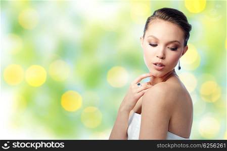 beauty, jewelry, people and luxury concept - beautiful asian woman or bride with earring and finger ring over summer green lights background