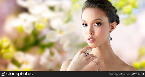 beauty, jewelry, people and luxury concept - beautiful asian woman or bride with earring, finger ring and pendant over natural spring lilac blossom background