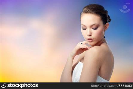 beauty, jewelry, people and luxury concept - beautiful asian woman or bride with earring and finger ring over pastel background. beautiful woman with earring and finger ring. beautiful woman with earring and finger ring
