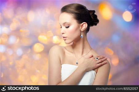 beauty, jewelry, people and luxury concept - beautiful asian woman or bride with earring, finger ring and pendant over holidays lights background. beautiful woman with earring, ring and pendant. beautiful woman with earring, ring and pendant