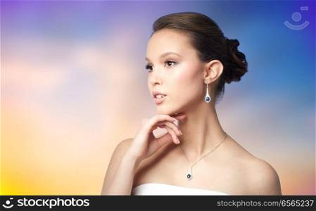 beauty, jewelry, people and luxury concept - beautiful asian woman or bride with earring and pendant over pastel background. beautiful asian woman with earring and pendant