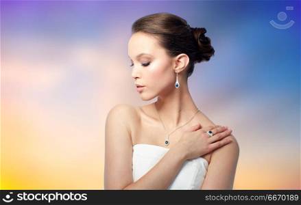 beauty, jewelry, people and luxury concept - beautiful asian woman or bride with earring, finger ring and pendant over pastel background. beautiful woman with earring, ring and pendant. beautiful woman with earring, ring and pendant