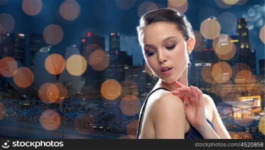 beauty, jewelry, people and luxury concept - beautiful young asian woman with earring over singapore city night lights background