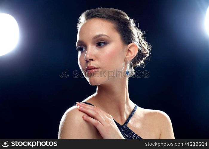 beauty, jewelry, people and luxury concept - beautiful young asian woman with earring over black background and spotlights