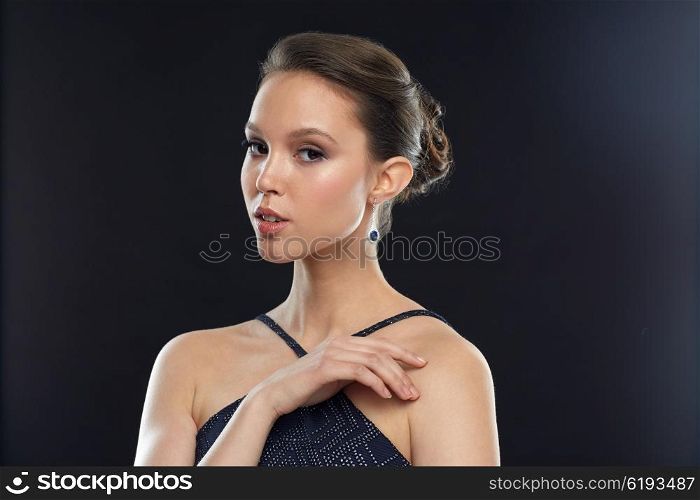 beauty, jewelry, people and luxury concept - beautiful young asian woman with earring over black background