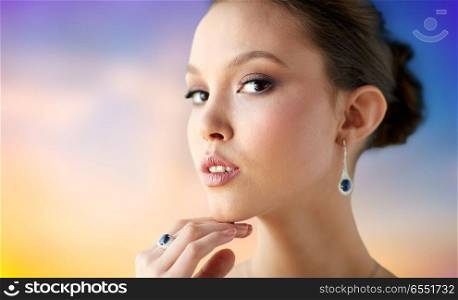 beauty, jewelry, people and luxury concept - close up of beautiful asian woman or bride with earring and finger ring over pastel background. beautiful woman with earring and finger ring. beautiful woman with earring and finger ring