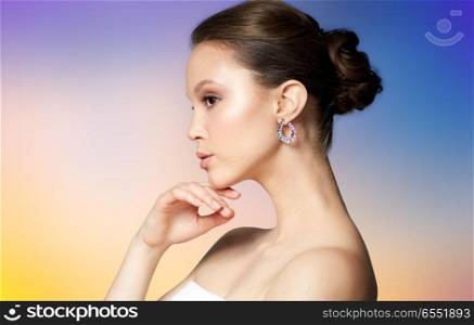 beauty, jewelry, people and luxury concept - close up of beautiful asian woman face with earring over pastel background. close up of beautiful woman face with earring. close up of beautiful woman face with earring