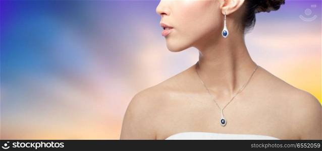 beauty, jewelry, people and luxury concept - close up of beautiful asian woman or bride with earring and pendant over pastel background. close up of woman with earring and pendant. close up of woman with earring and pendant