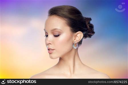 beauty, jewelry, people and luxury concept - close up of beautiful asian woman face with earring over pastel background. close up of beautiful woman face with earring