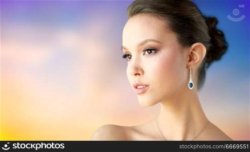 beauty, jewelry, people and luxury concept - close up of beautiful asian woman or bride with earring over pastel background. close up of beautiful woman face with earring. close up of beautiful woman face with earring
