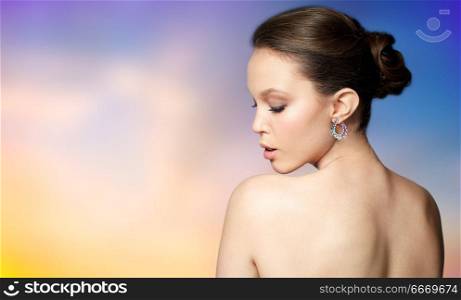 beauty, jewelry, people and luxury concept - close up of beautiful asian woman face with earring over pastel background. close up of beautiful woman face with earring. close up of beautiful woman face with earring
