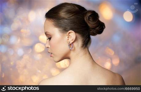 beauty, jewelry, people and luxury concept - close up of beautiful asian woman face with earring over holidays lights background. close up of beautiful woman face with earring. close up of beautiful woman face with earring