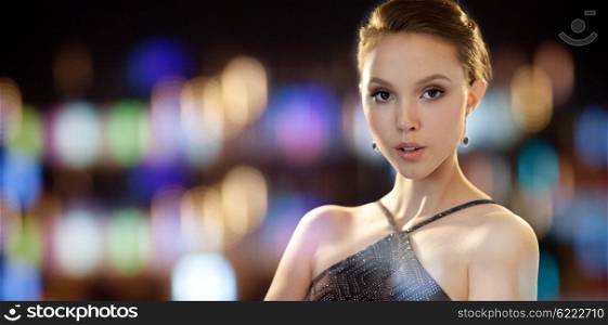 beauty, jewelry, people and luxury concept - face of beautiful young asian woman with earring over night lights background