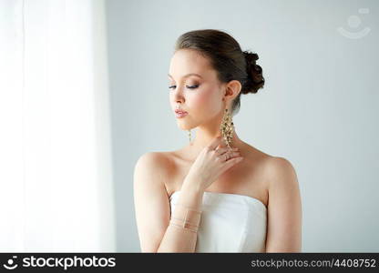 beauty, jewelry, wedding accessories, people and luxury concept - beautiful asian woman in white dress or bride with golden earrings and bracelet