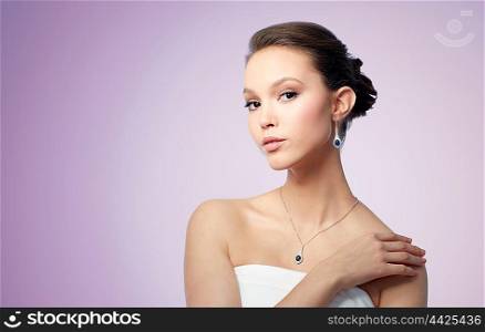 beauty, jewelry, wedding accessories, people and luxury concept - beautiful asian woman or bride with earring and pendant over violet background
