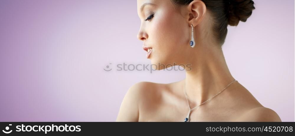 beauty, jewelry, wedding accessories, people and luxury concept - beautiful asian woman or bride with earring and pendant over violet background