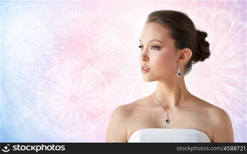 beauty, jewelry, wedding accessories, people and luxury concept - beautiful asian woman or bride with earring and pendant over rose quartz and serenity patterned background
