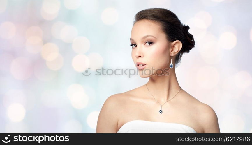 beauty, jewelry, wedding accessories, people and luxury concept - beautiful asian woman or bride with earring and pendant over holidays lights background
