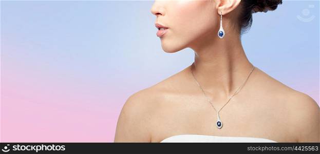 beauty, jewelry, wedding accessories, people and luxury concept - close up of beautiful asian woman or bride with earring and pendant over rose quartz and serenity gradient background