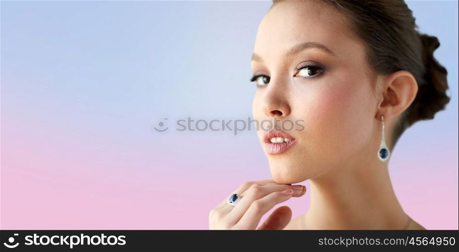 beauty, jewelry, wedding accessories, people and luxury concept - close up of beautiful asian woman or bride with earring and finger ring over rose quartz and serenity gradient background