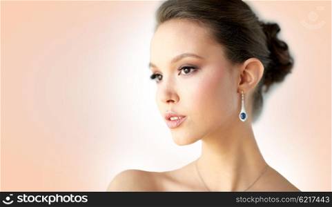 beauty, jewelry, wedding accessories, people and luxury concept - close up of beautiful asian woman or bride with earring over beige background