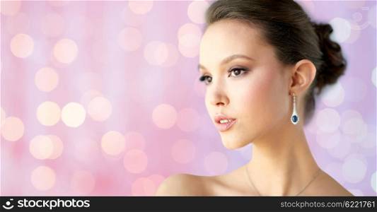 beauty, jewelry, wedding accessories, people and luxury concept - close up of beautiful asian woman or bride with earring over holidays lights background