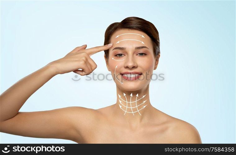 beauty, lifting and plastic surgery concept - beautiful young woman with arrows on her face and neck over blue background. beautiful young woman with bare shoulder