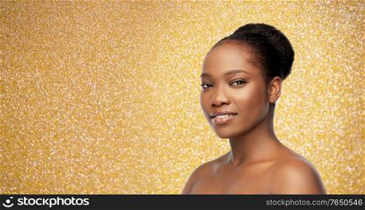 beauty, luxury and people concept - portrait of happy smiling young african american woman with bare shoulders over golden glitter on background. portrait of young african american woman