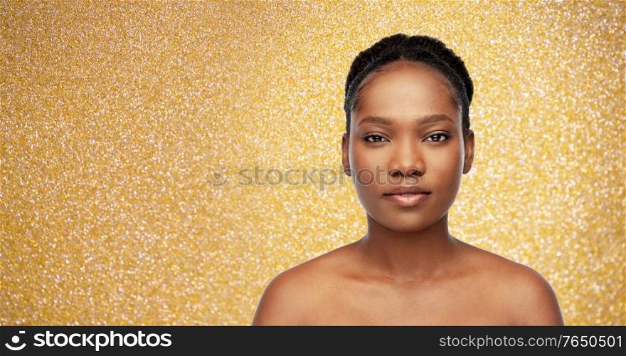 beauty, luxury and people concept - portrait of young african american woman with bare shoulders over golden glitter on background. portrait of young african american woman