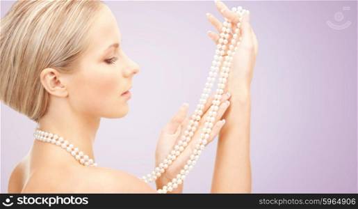 beauty, luxury, people, advertisement and jewelry concept - beautiful woman with sea pearl necklace or beads in hand over violet background