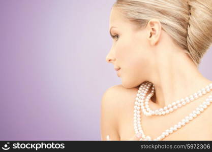 beauty, luxury, people, advertisement and jewelry concept - beautiful woman with sea pearl necklace or beads over violet background