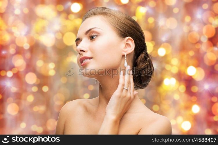 beauty, luxury, people, holidays and jewelry concept - beautiful woman with diamond ring and earrings over lights background