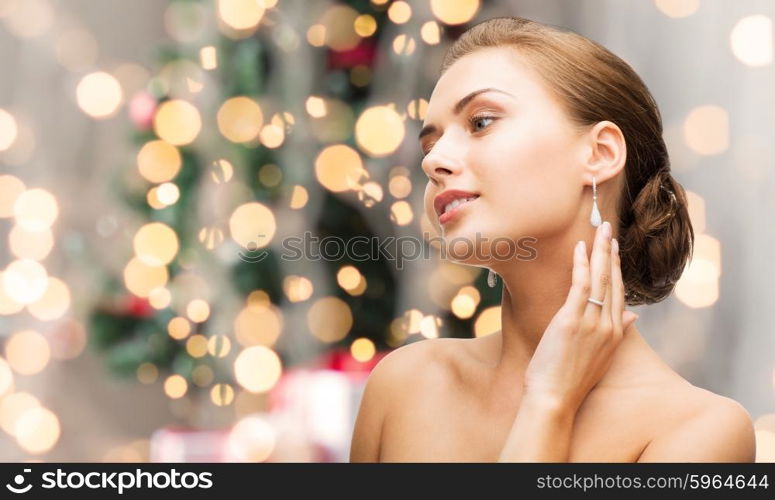 beauty, luxury, people, holidays and jewelry concept - beautiful woman with diamond earrings over christmas lights background