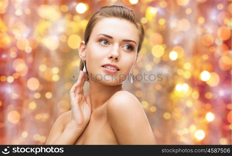 beauty, luxury, people, holidays and jewelry concept - beautiful woman with diamond earrings over lights background