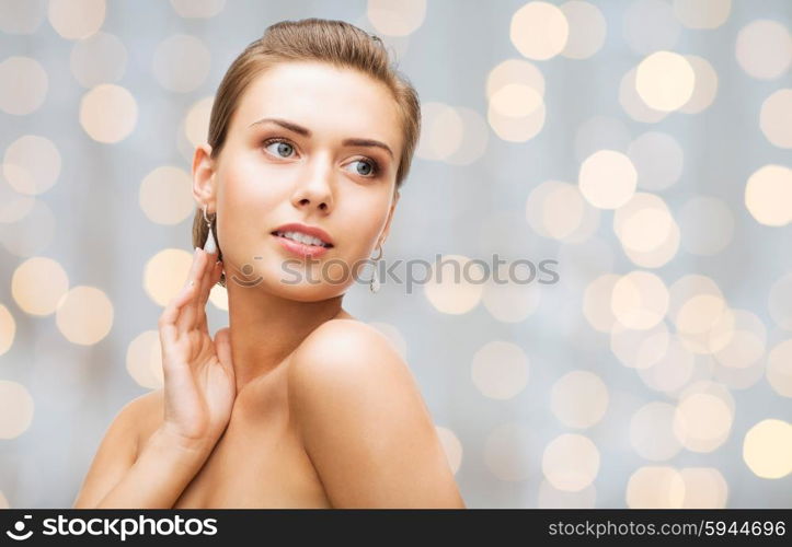 beauty, luxury, people, holidays and jewelry concept - beautiful woman with diamond earrings over lights background