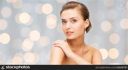 beauty, luxury, people, holidays and jewelry concept - beautiful woman with diamond earrings over lights background