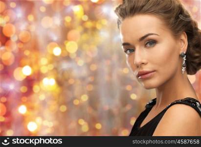 beauty, luxury, people, holidays and jewelry concept - beautiful woman with gem stone earrings over lights background