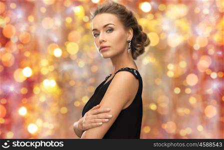 beauty, luxury, people, holidays and jewelry concept - beautiful woman with gem stone earrings over lights background