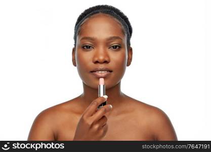 beauty, make up and cosmetics concept - beautiful young african american woman applying lipstick over white background. african american woman applying lipstick