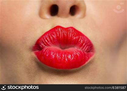 beauty, make up and mouth expression concept - close up of woman lips with red lipstick making kissing or duck face. woman lips with red lipstick making kiss