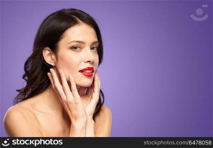 beauty, make up and people concept - beautiful young woman with red lipstick over ultra violet background touching her face. beautiful young woman with red lipstick. beautiful young woman with red lipstick
