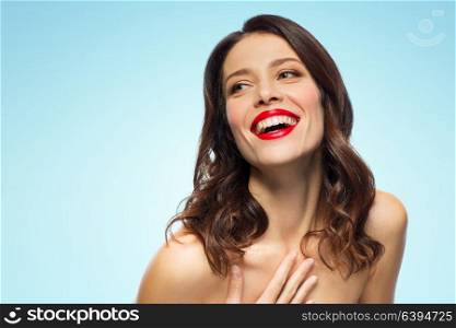 beauty, make up and people concept - happy laughing young woman with red lipstick over blue background. beautiful laughing young woman with red lipstick