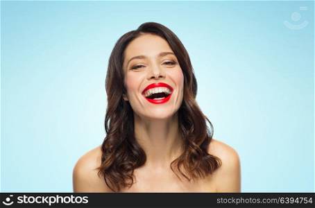 beauty, make up and people concept - happy laughing young woman with red lipstick over blue background. beautiful laughing young woman with red lipstick