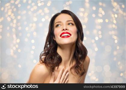beauty, make up and people concept - happy smiling young woman with red lipstick posing over holidays lights background. beautiful smiling young woman with red lipstick. beautiful smiling young woman with red lipstick