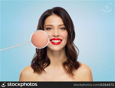 beauty, make up and people concept - happy smiling young woman with magnified smooth facial skin area over blue background. beautiful woman with magnified smooth facial skin