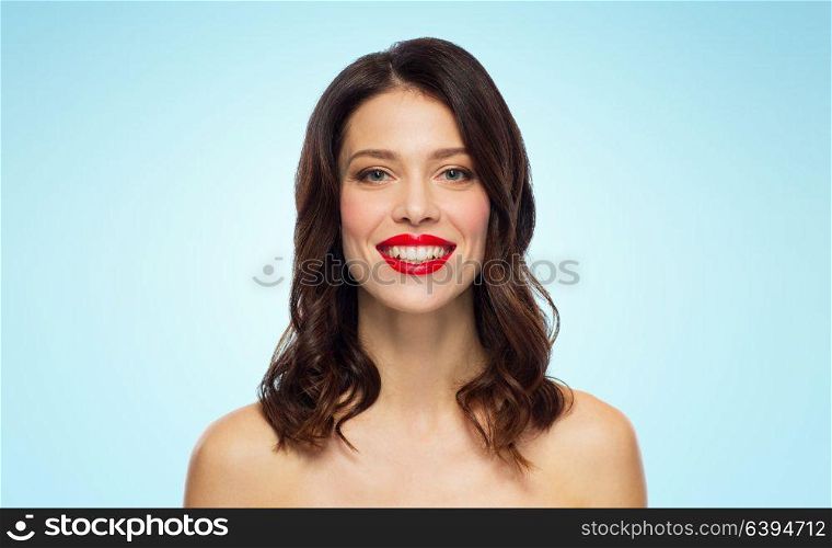 beauty, make up and people concept - happy smiling young woman with red lipstick over blue background. beautiful smiling young woman with red lipstick