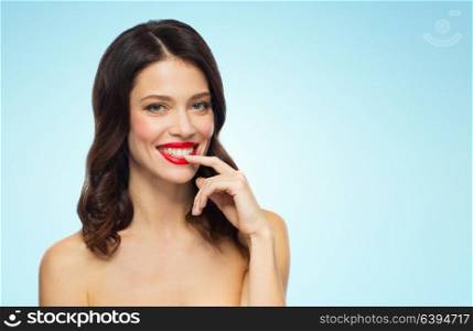 beauty, make up and people concept - happy smiling young woman with red lipstick posing over blue background. beautiful smiling young woman with red lipstick